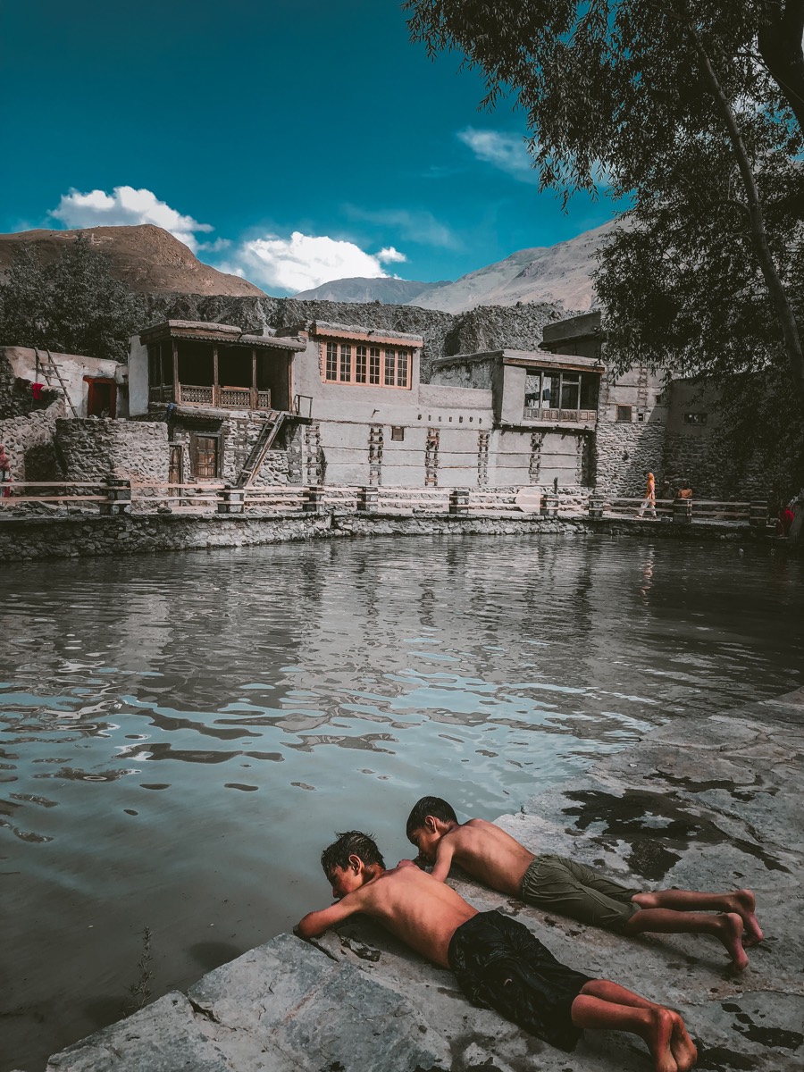 Two boys lying on the stone edge of a village pool